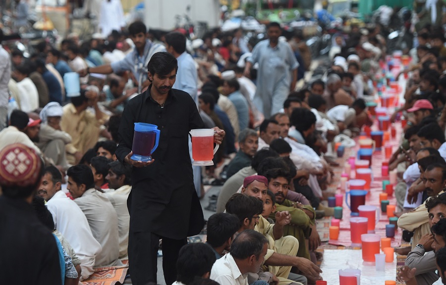 A Pakistani volunteer distributes drinks as devotees prepare to break the Ramadan fast on the first day of holy month of Ramadan in Rawalpindi on June 7, 2016. / AFP / FAROOQ NAEEM